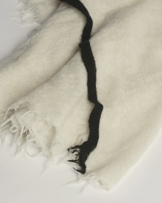 Close-up of a Milk X Black, 100% Cashmere scarf with black detailing and frayed edges, the Rosa Cashmere Scarf by Grisal.