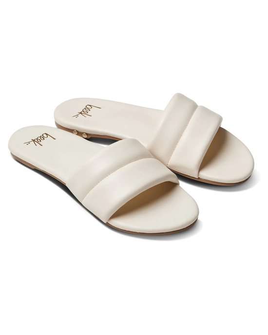 A pair of cream-colored beek. Sugarbird slide sandals with a molded footbed on a white background.