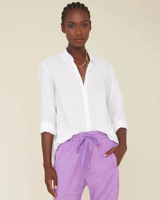 A woman wearing a XiRENA Beau Top in White and lilac trousers stands against a neutral background.